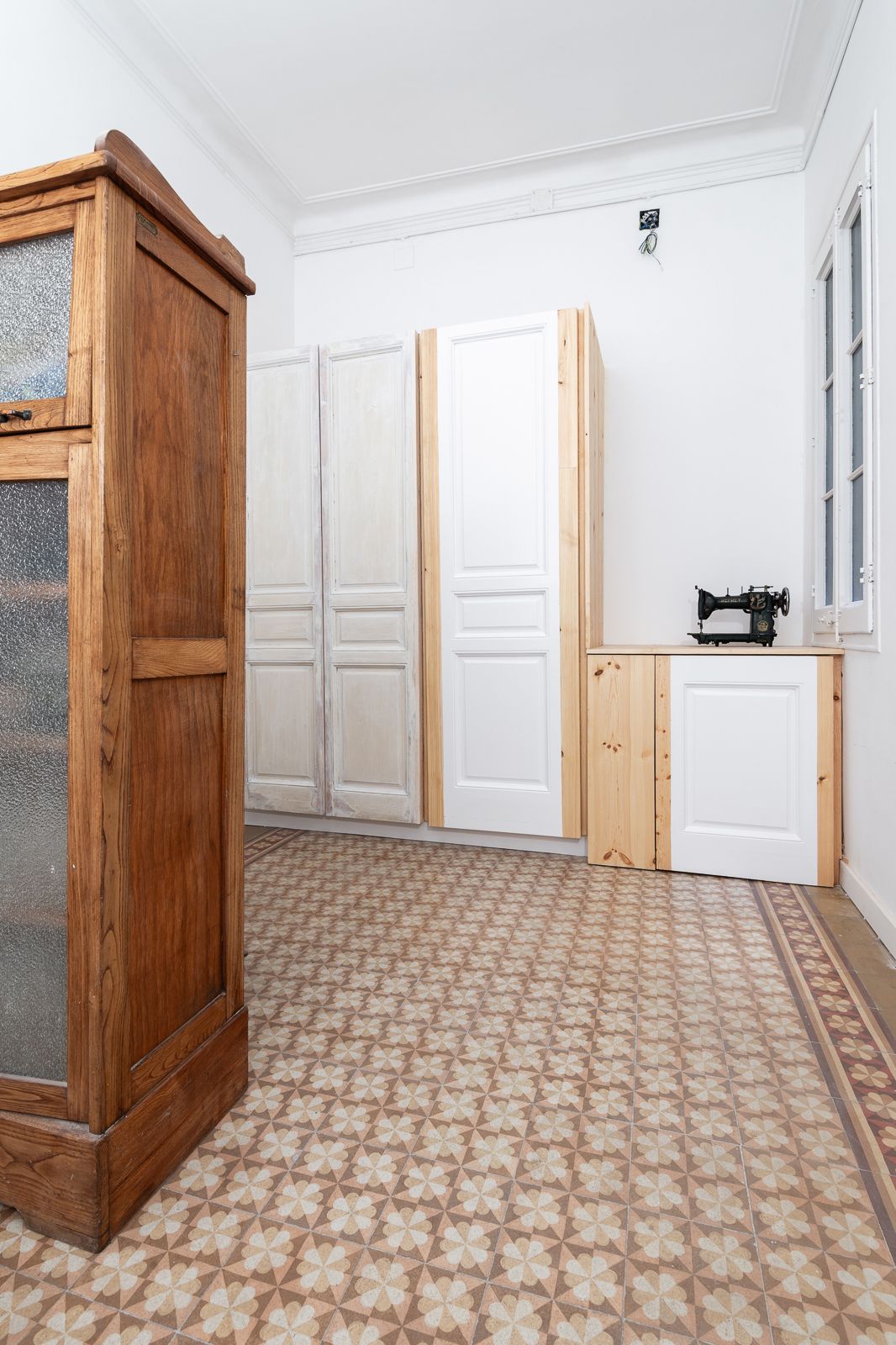Room with vintage furniture, patterned floor tiles, and a sewing machine on a wooden cabinet.