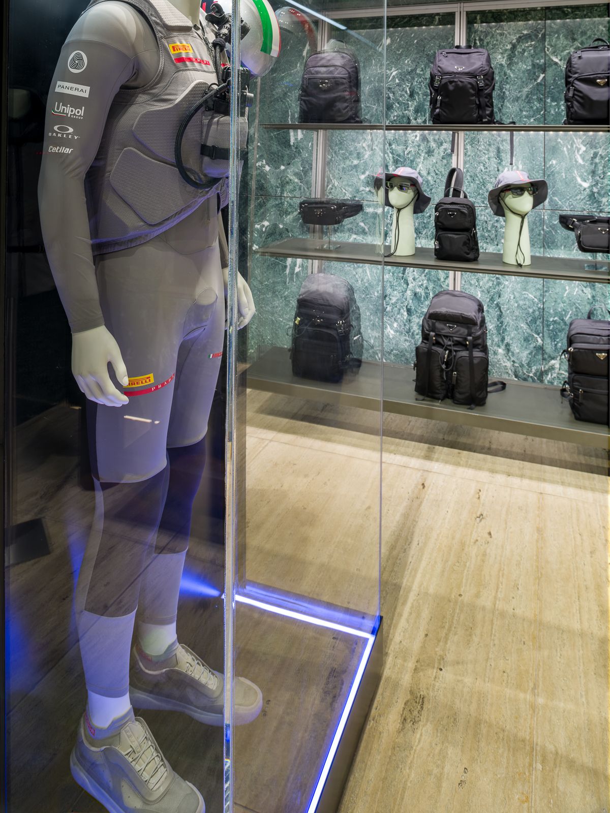 Luxury Prada boutique with green marble walls, showcasing a mannequin in a performance outfit encased in a glass display.