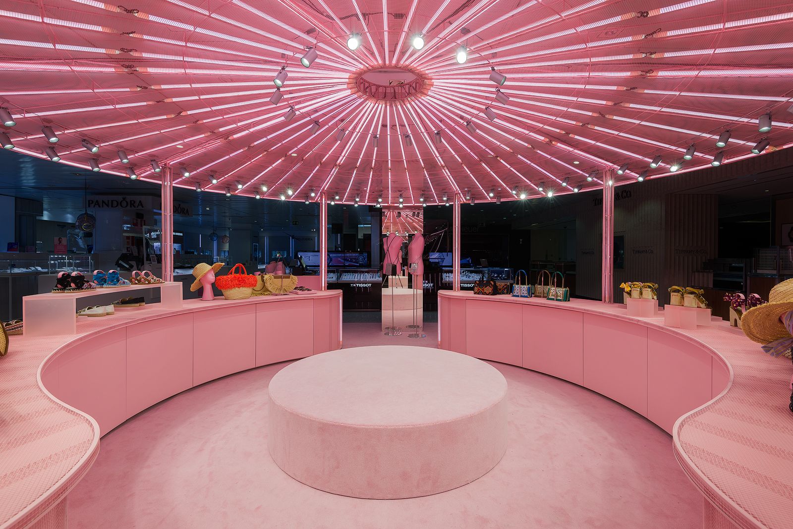 Central circular display area in Miu Miu's pink pop-up store with illuminated ceiling and merchandise.