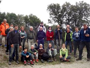 A group of people posing together outdoors on a trail with trees in the background.