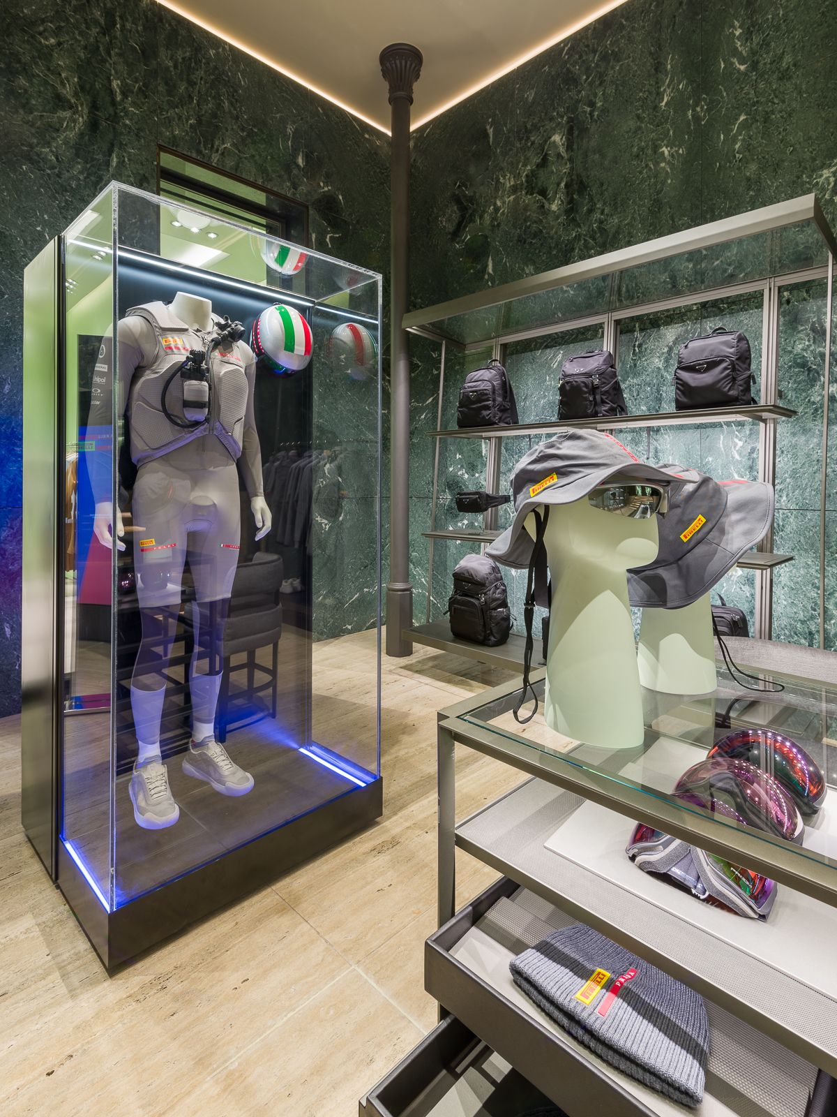 Luxury Prada boutique with green marble walls, showcasing a mannequin in a performance outfit encased in a glass display.